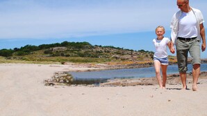 Een strand met een rotsachtige kustlijn en een wateroppervlak.