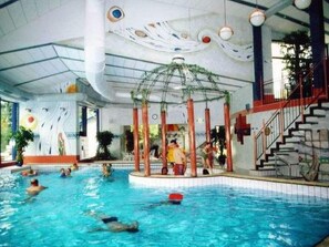 Une piscine intérieure dotée d’une structure centrale, entourée d’escaliers et d’une rambarde.