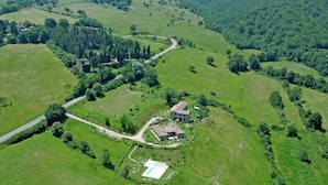 An aerial view of a rural property with a large house, a swimming pool, and surrounding green fields. - Stunning Farmhouse in Passignano With Pool (Passignano sul Trasimeno)