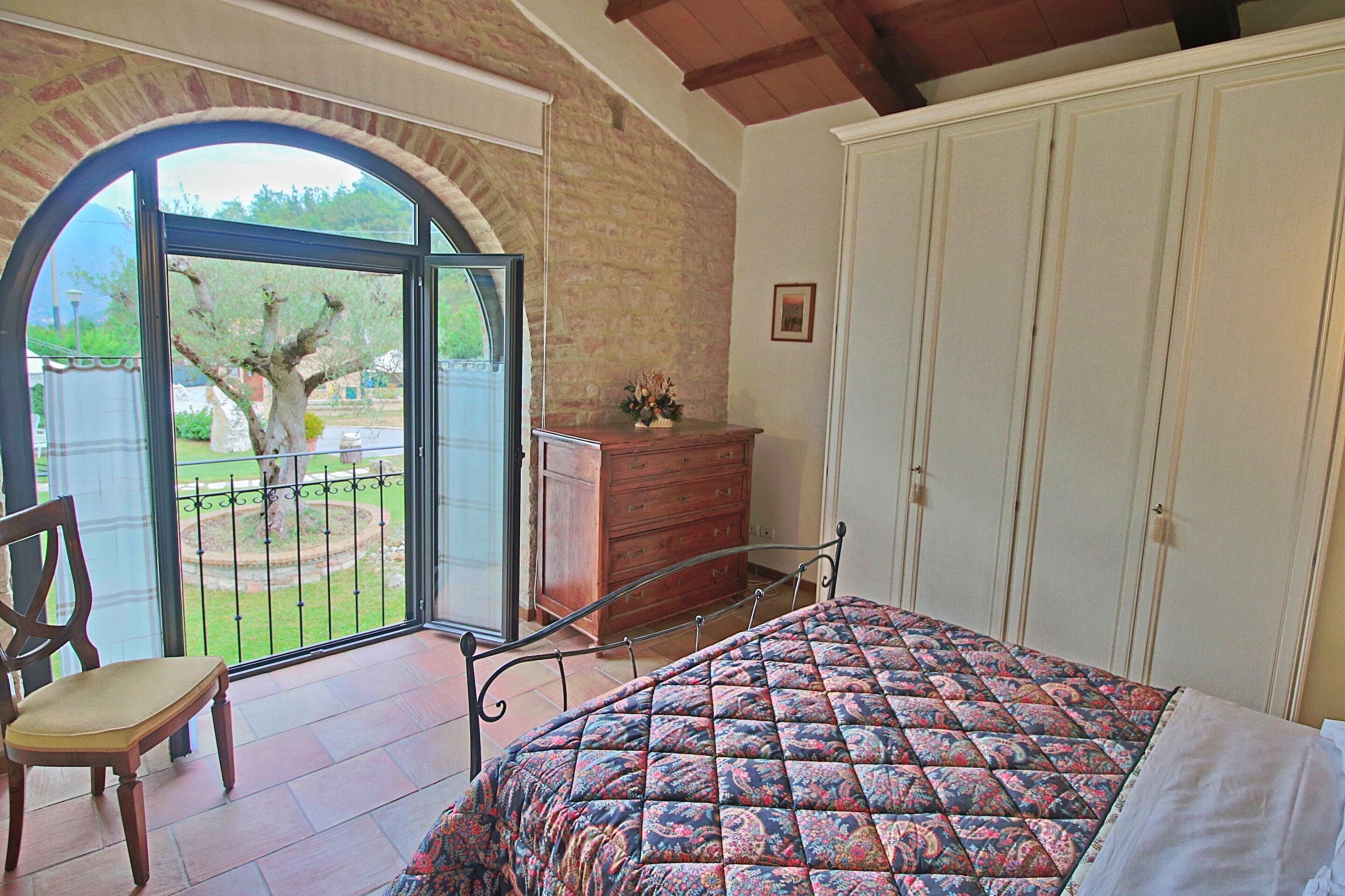 Un dormitorio con cama, una silla, cómoda y armario.