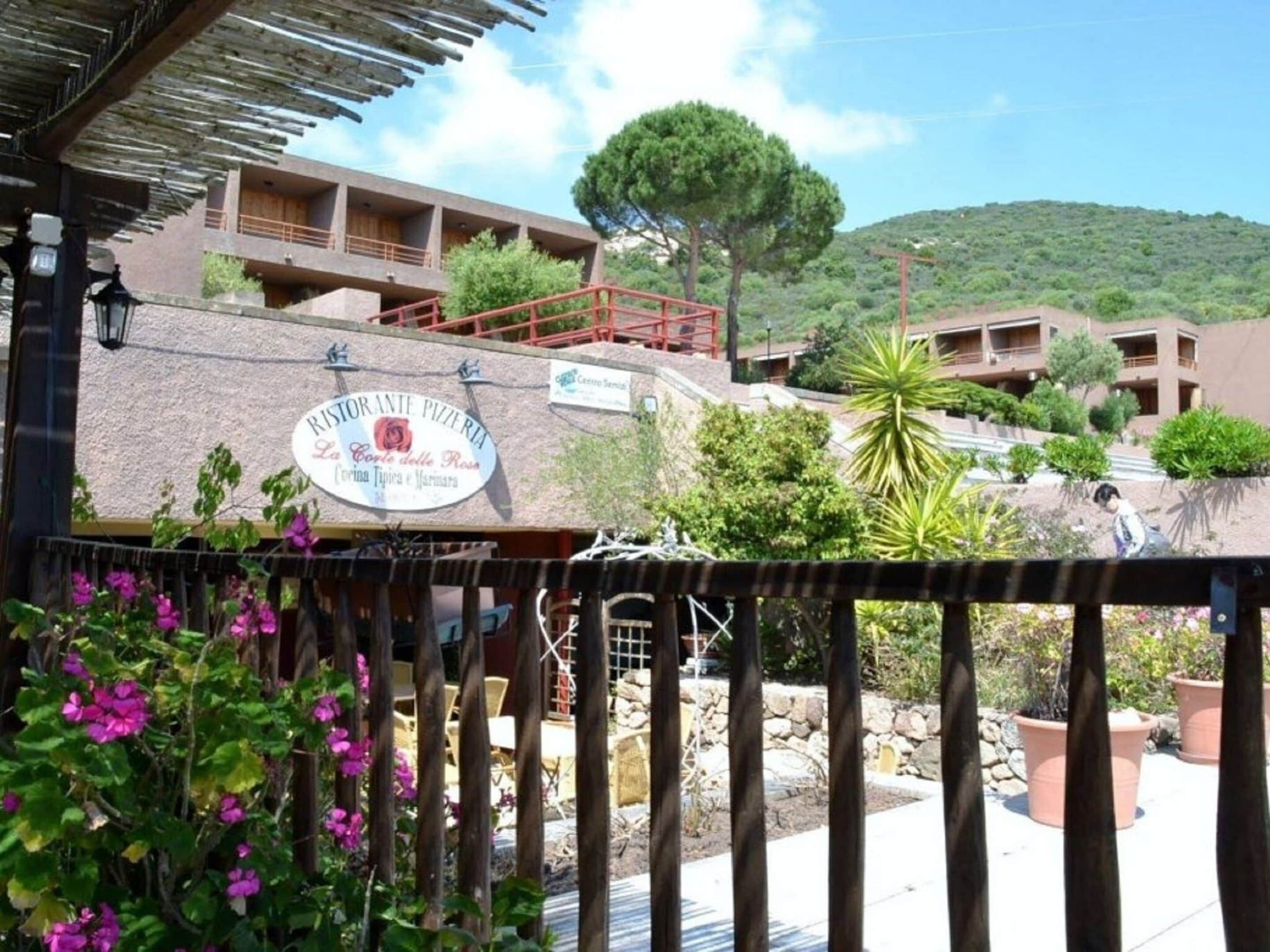 A restaurant with outdoor seating, surrounded by greenery and a hillside.