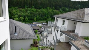 A multi-story building with a rooftop terrace, a reception area, and a view of a forested hillside. - Holiday Home in the Centre of Willingen With View (Willingen)
