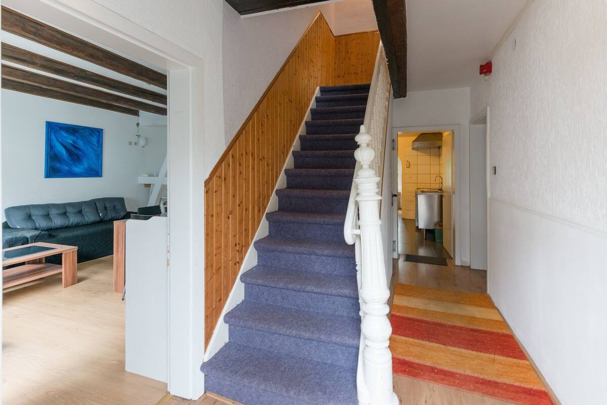 A staircase with wooden handrails and carpeted steps leading to a landing.