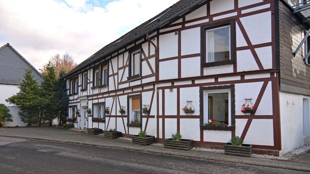 Ein traditionelles Fachwerkhäuschen mit vielen Fenstern, einige mit Blumenkästen.