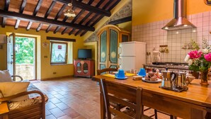 A cozy kitchen with wooden beams, a tiled backsplash, and a dining area with a table set for two. - Farmhouse in Hilly Area in Gubbio With Pool (Gubbio)