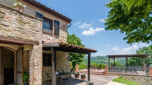 A stone building with a patio, outdoor seating, and a view of the countryside. - Farmhouse in Hilly Area in Gubbio With Pool (Gubbio)