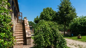 A stone staircase leading to a wooden door, surrounded by lush greenery and a clear blue sky. - Farmhouse in Hilly Area in Gubbio With Pool (Gubbio)