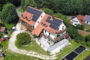 Una casa a due piani con pannelli solari sul tetto, immersa nel verde e con vialetto in ghiaia.
