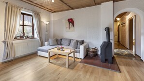 Een gezellige woonkamer met een bank, een salontafel, een open haard en een raam met gordijnen.