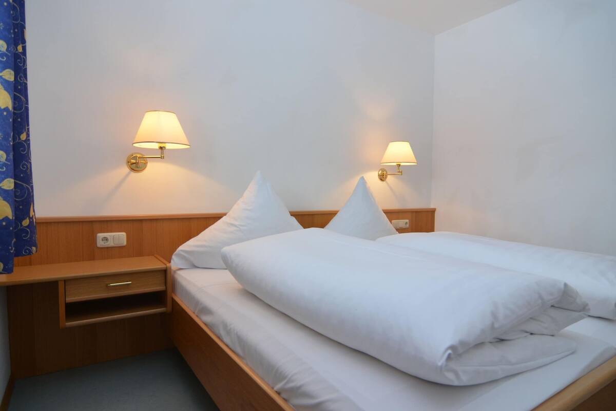 A hotel room with a wooden bed, two bedside tables, and wall-mounted lamps.