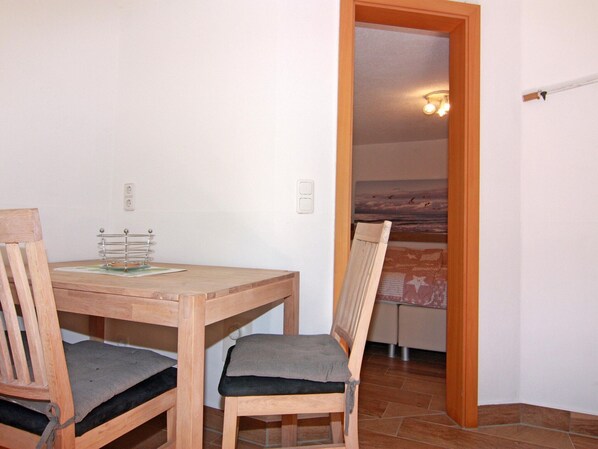 A wooden dining table with two chairs, a small table lamp, and a painting on the wall. - Peaceful Apartment in Ostseebad Boltenhagen With Terrace (Boltenhagen)