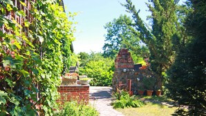 Ein Backsteinhaus mit einem steinernen Weg, der zu einer Steinstruktur mit Schornstein führt.