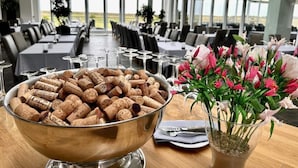 A dining area with tables set for a meal, a bowl of wine corks, and a vase of flowers. - 4 Person Holiday Home on a Holiday Park in Romo (Rømø)