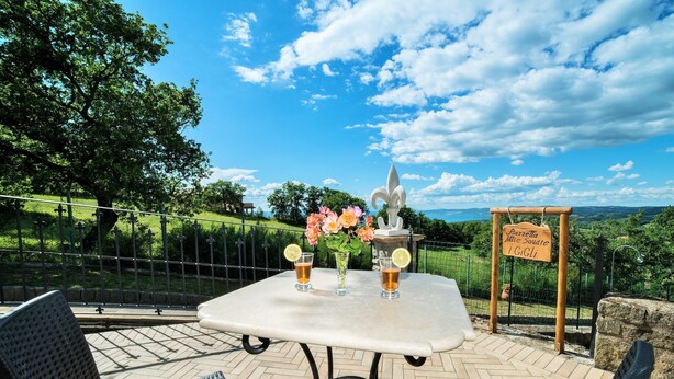 Eine Terrasse im Freien mit einem Tisch für zwei Personen, inklusive einer Vase mit Blumen und zwei Biergläsern.