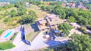 Vista aérea de un edificio de varios pisos con piscina, zona de estar exterior y jardín ajardinado.