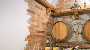 Ein Holztisch für Weinproben mit drei Weingläsern und zwei Weinflaschen, vor einer Ziegelwand mit Kamin aus Stein.