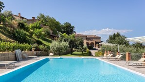 A swimming pool with lounge chairs, surrounded by greenery and buildings. - Lavish Holiday Home in Volterra With Pool (Volterra)