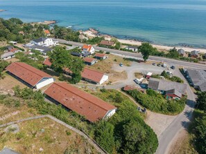 Vue aérienne d’une zone résidentielle côtière, avec des maisons, une route et une plage.