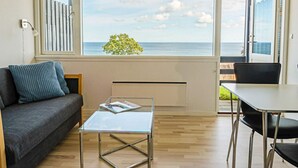 Una sala de estar moderna con un sofá, una mesa de centro de vidrio y vistas al mar a través de amplios ventanales.