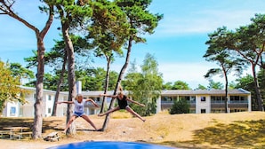 Un'area giochi con uno scivolo e alberi, con un edificio sullo sfondo.