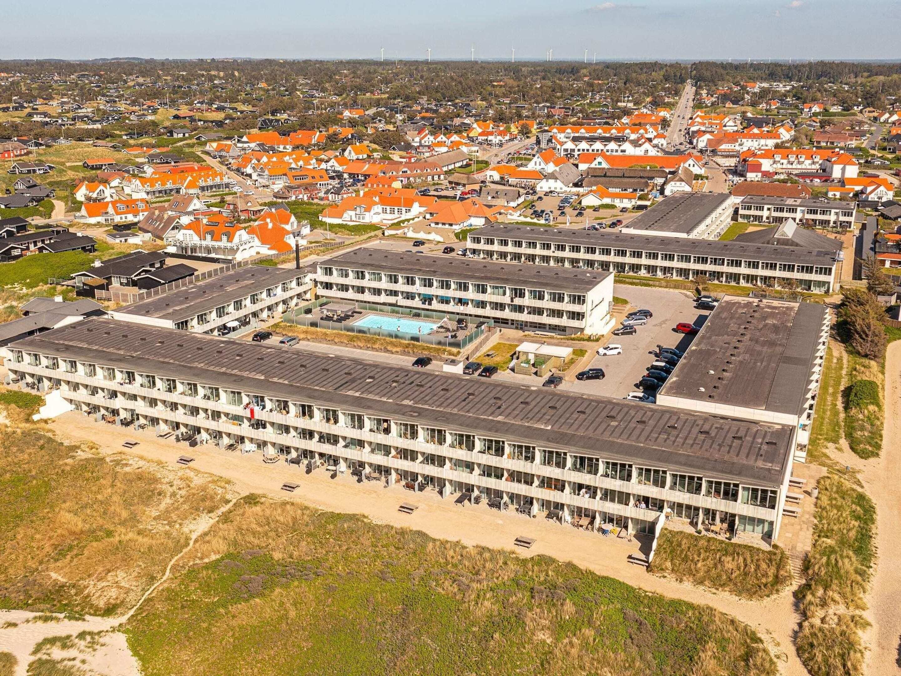 A modern hotel with a central courtyard, multiple floors, and a parking area.