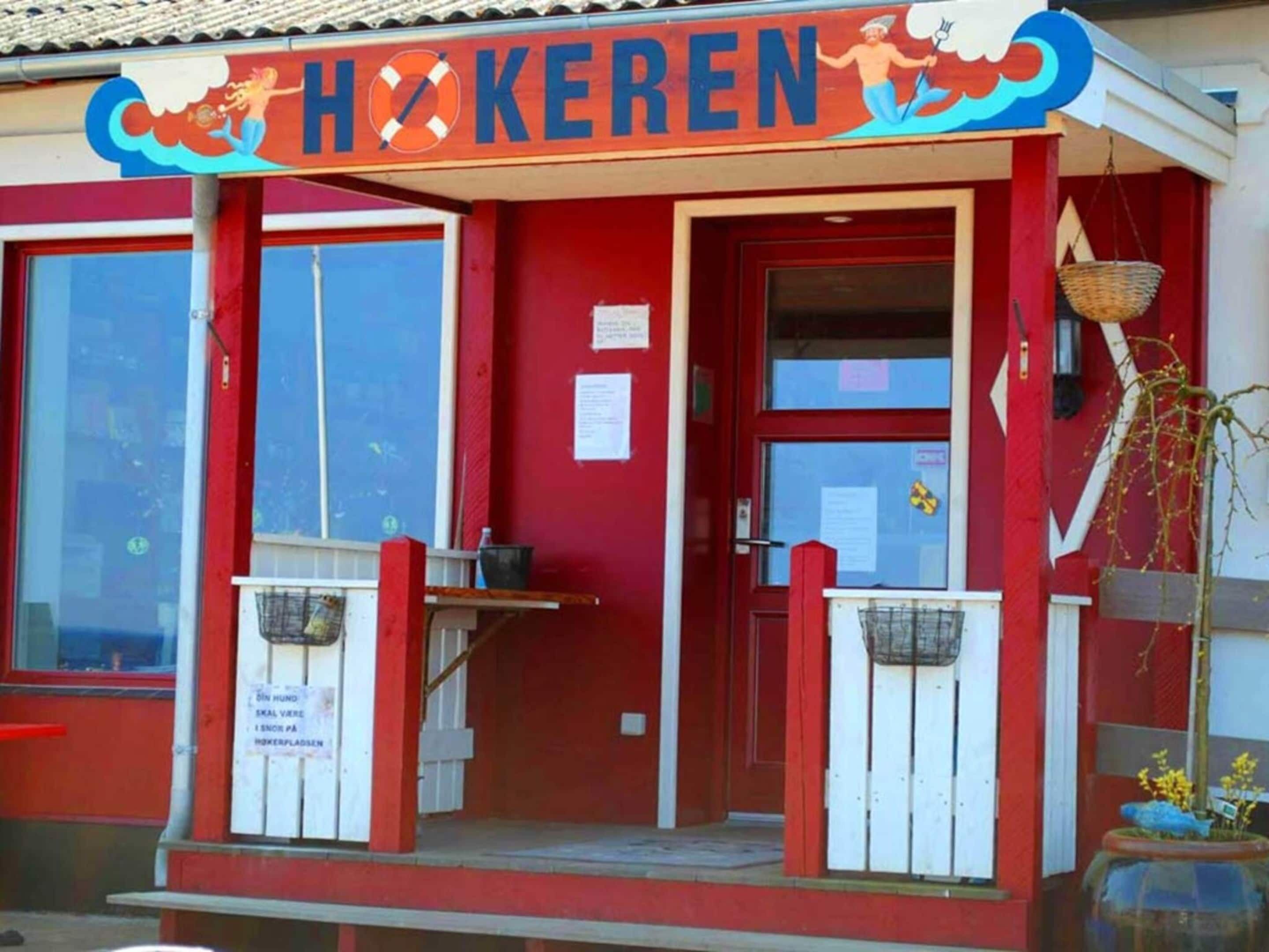 Um edifício vermelho com uma placa que diz "HOKEREN" e uma grande janela.