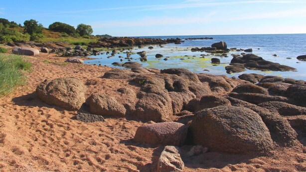 A rocky beach with large boulders and a clear view of the sea. - 4 Person Holiday Home in Svaneke (Svaneke)