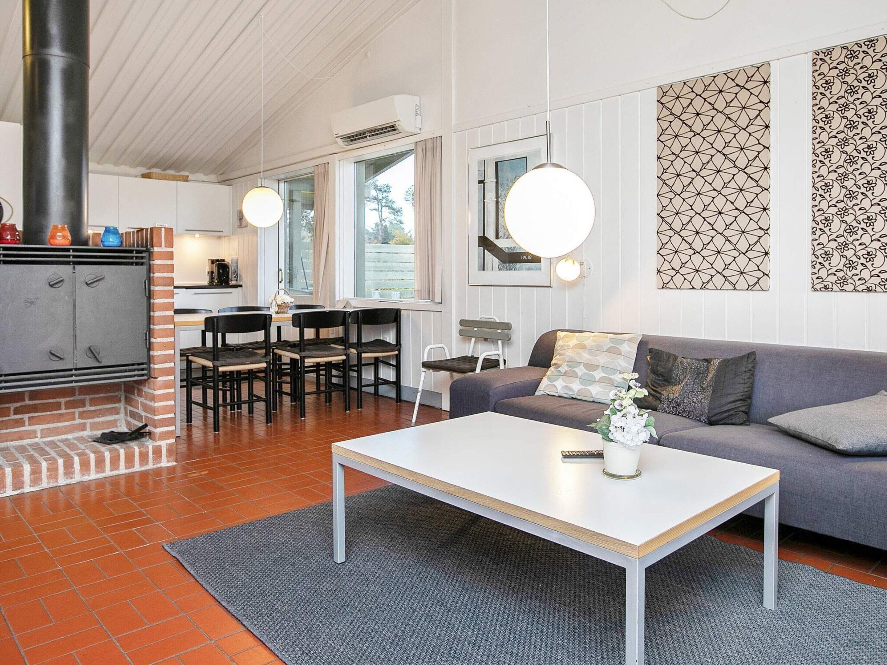 Ett modernt vardagsrum med en öppen spis, en soffa, ett soffbord och en matplats med stolar.
