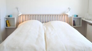 A double bed with a white headboard and two bedside tables with lamps. - 4 Person Holiday Home in Svaneke (Svaneke)