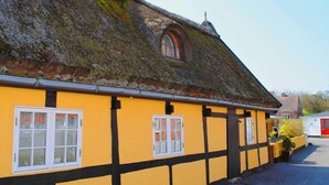 A traditional yellow building with black timber framing and a thatched roof. - 4 Person Holiday Home in Svaneke (Svaneke)