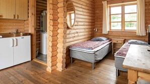 Ein rustikales Blockhaus-Interieur mit Küche, einem Bett und einem Essbereich.