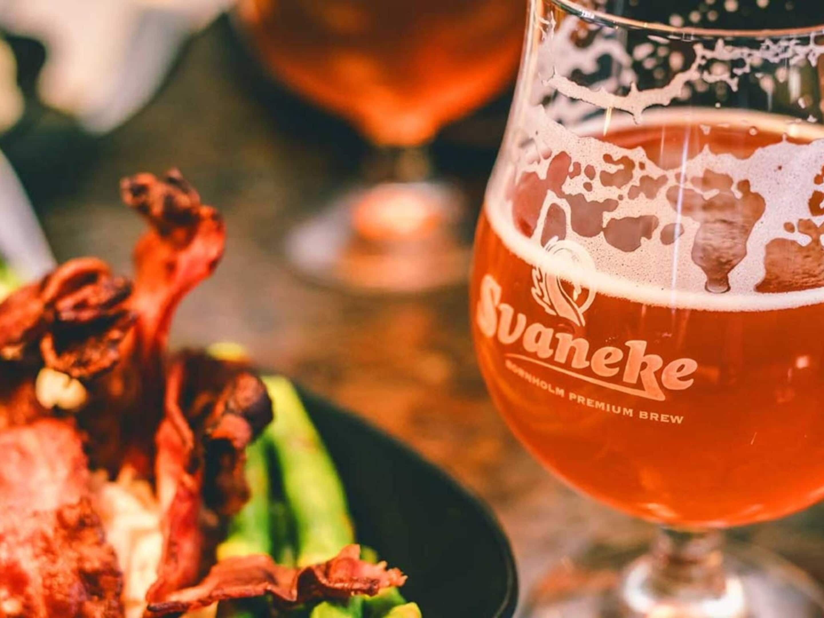 Un verre de bière Svanecke, accompagné d’un canard rôti et de légumes, sur la table.