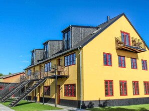 Un bâtiment jaune avec des fenêtres rouges et un balcon.