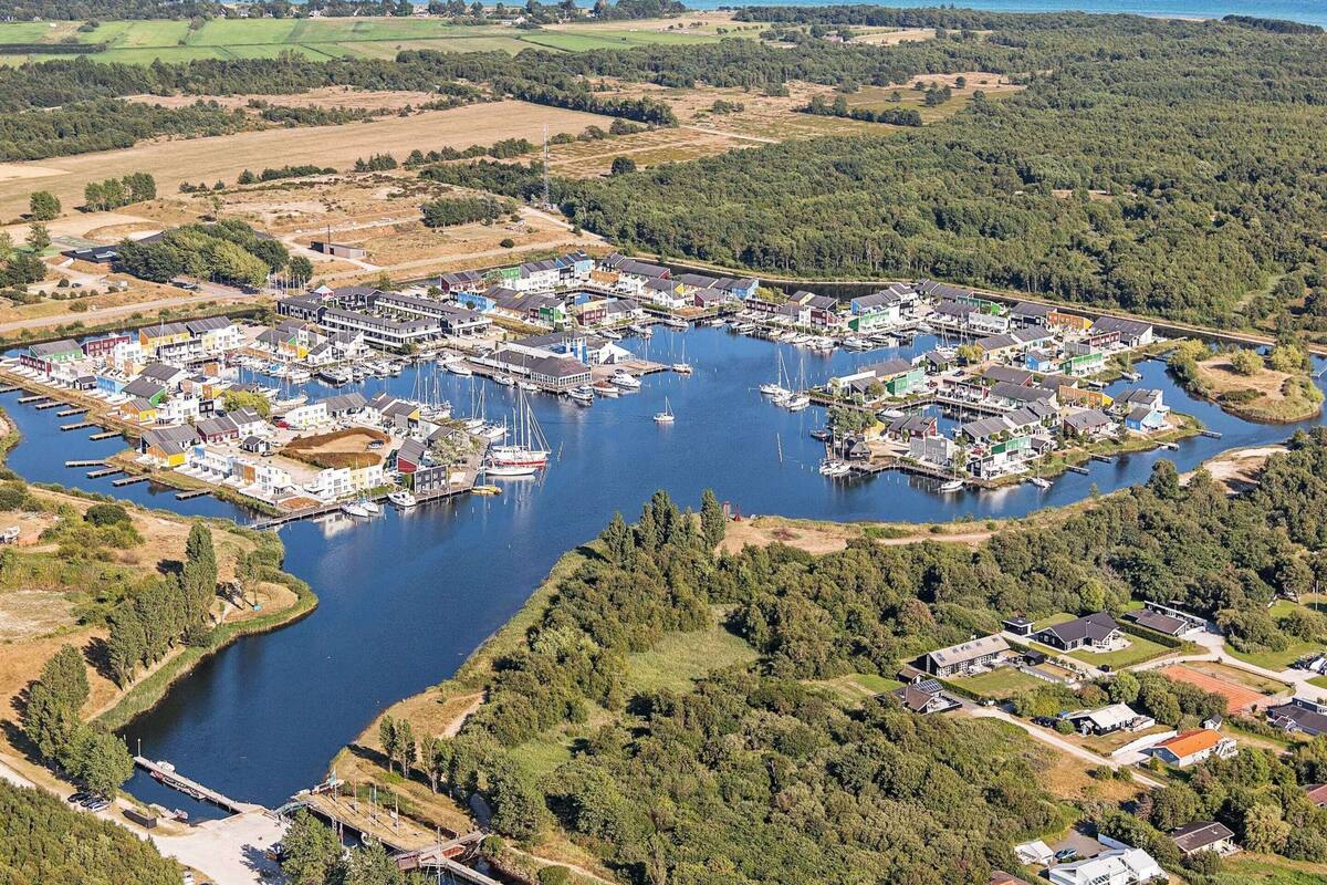 An aerial view of a marina with numerous boats docked, surrounded by residential buildings and greenery.