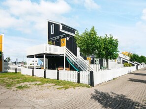 A modern building with a flat roof, a staircase, and a white fence.