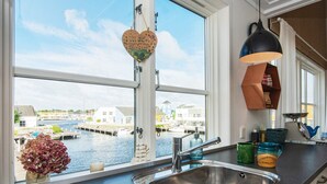 Cucina con un'ampia finestra che si affaccia su una marina, un lavello in acciaio inossidabile e una lampada a sospensione.