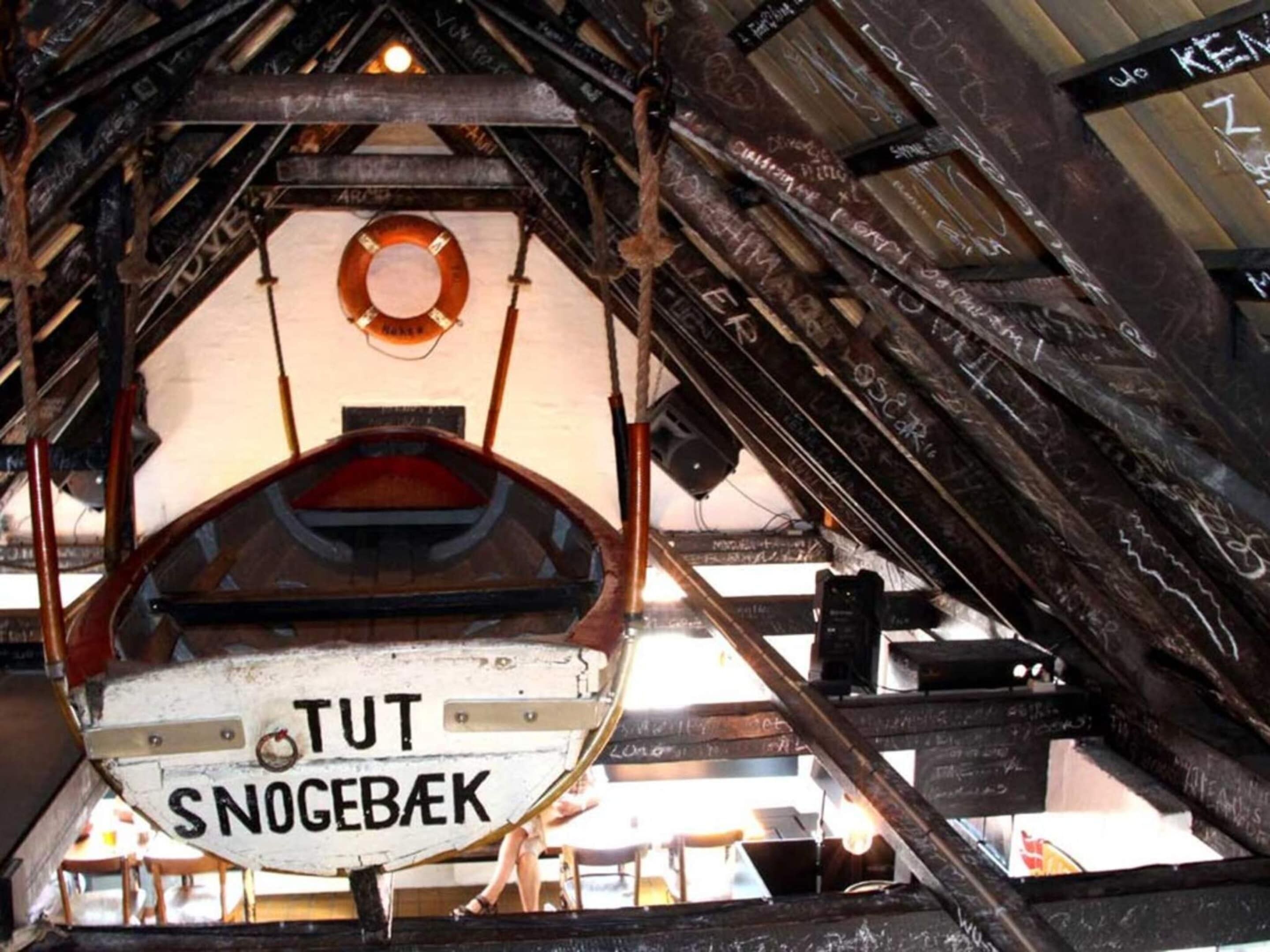 Un interior rústico con vigas a la vista y un letrero que dice "TUT SNOGEBAK".