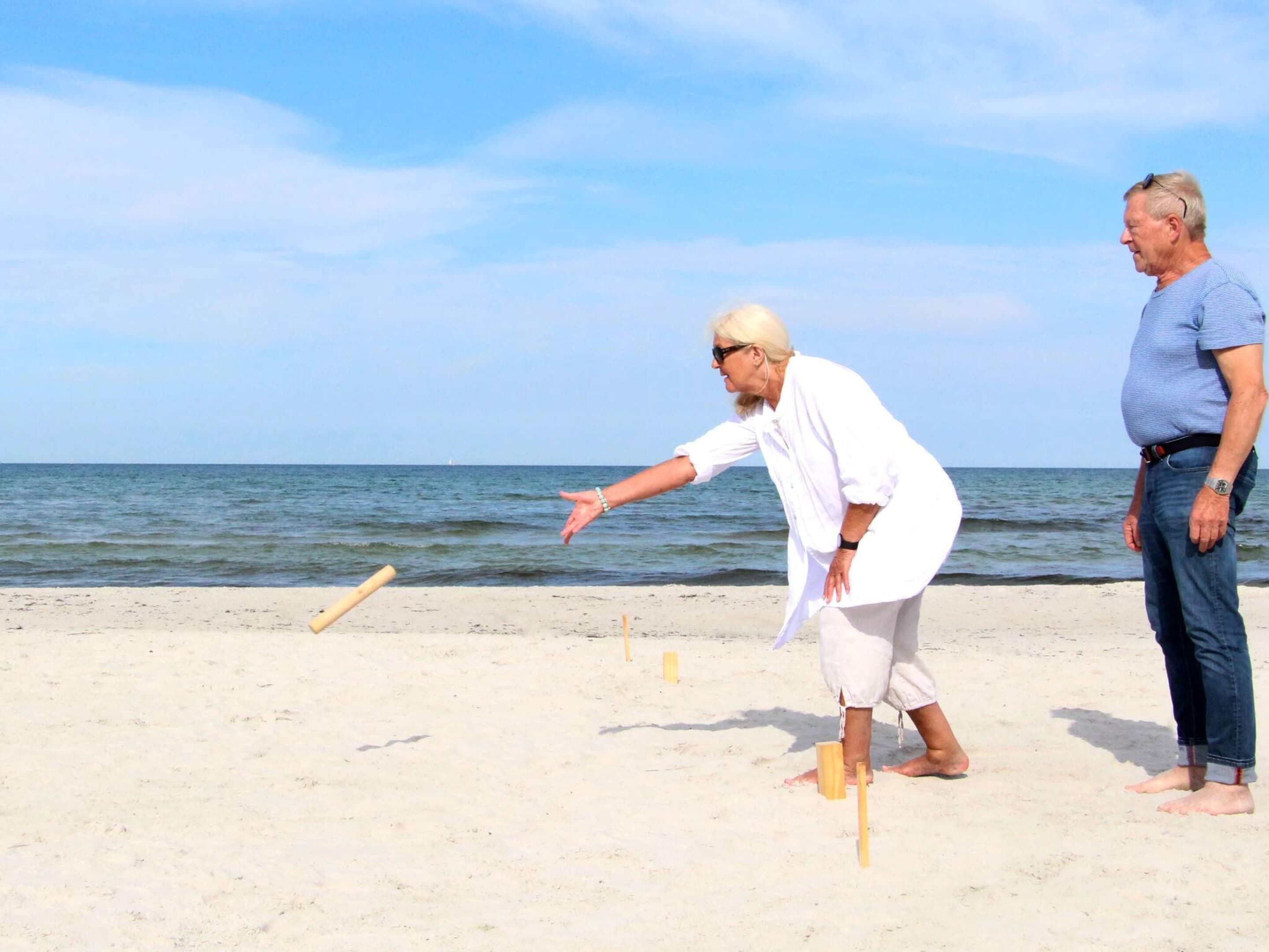 Two people playing a game on a beach with the ocean in the background.