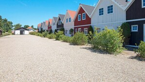 Une rangée de maisons aux couleurs vives, avec une allée en gravier et de la verdure devant.