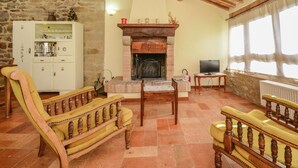 A cozy living room with a fireplace, wooden furniture, and a stone wall. - Modern Holiday Home in Monte Santa Maria Tiberina (Monte Santa Maria Tiberina)
