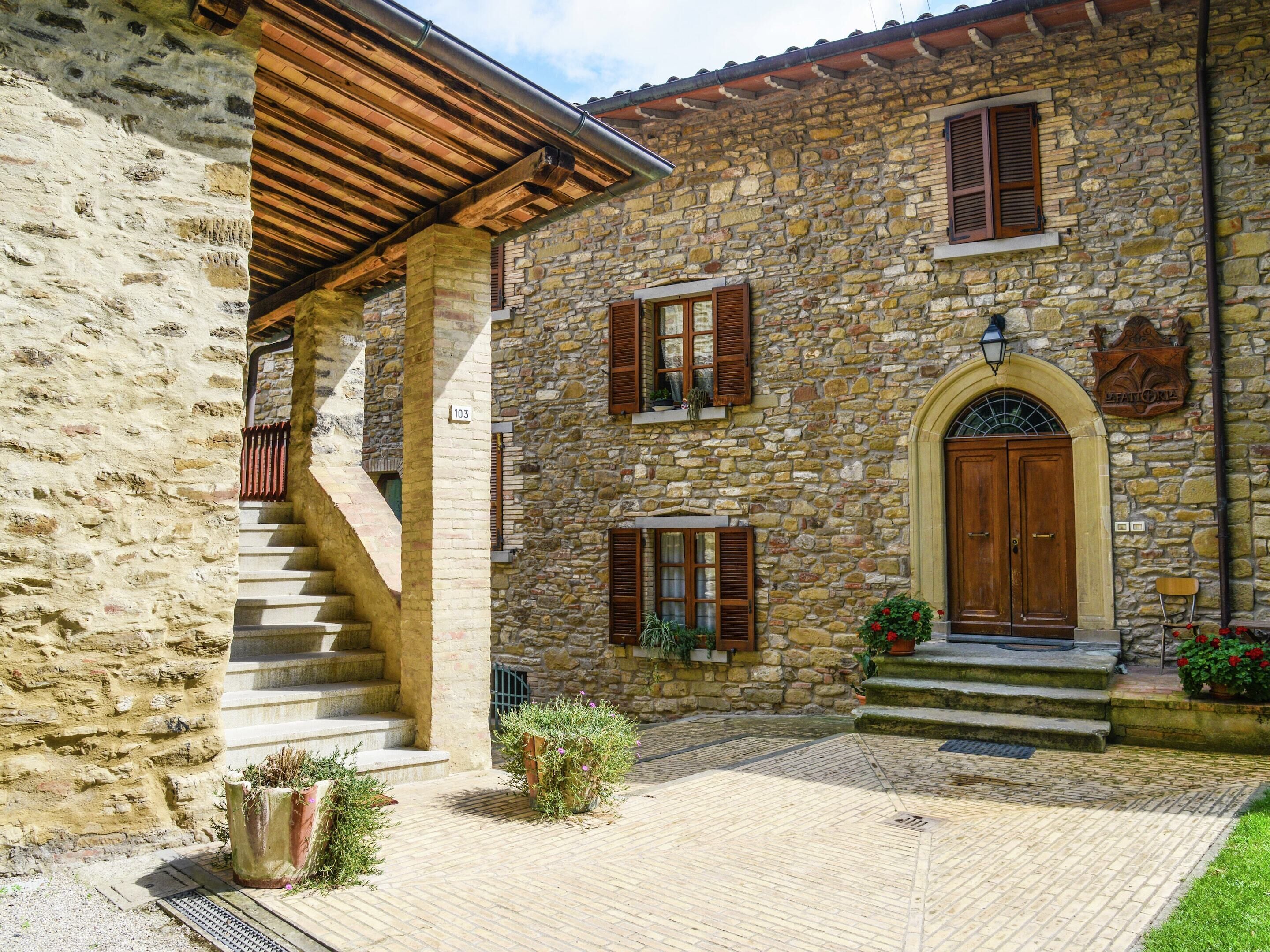 A stone building with a wooden staircase leading to a covered porch.