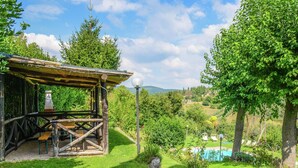 A rustic wooden structure with a thatched roof, a stone wall, and a view of a swimming pool and lush greenery. - Modern Holiday Home in Monte Santa Maria Tiberina (Monte Santa Maria Tiberina)