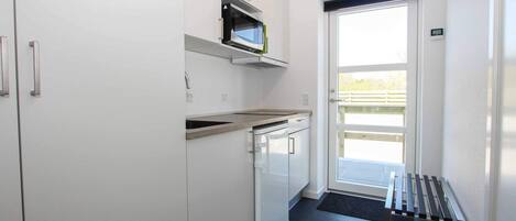 Una cocina moderna con armarios blancos, microondas y una campana extractora de acero inoxidable.