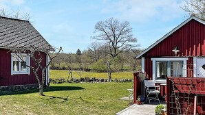 Zwei rote Holzhäuser mit weißen Verzierungen, ein grüner Rasen und ein klarer, blauer Himmel.