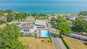 An aerial view of a coastal property with a swimming pool, multiple buildings, and a clear view of the ocean. - 2 Person Holiday Home in Allinge (Allinge)