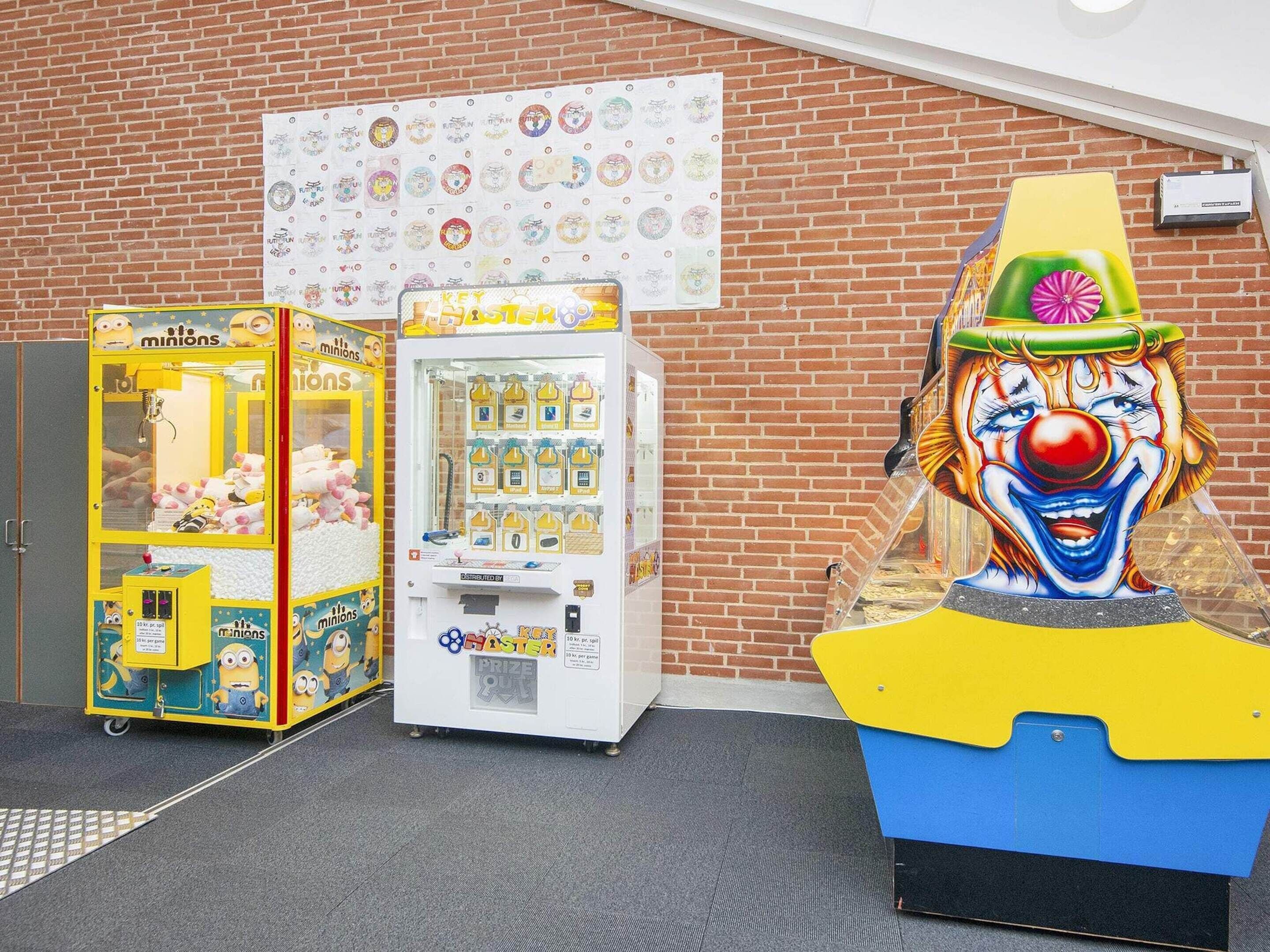 Un bâtiment en briques, avec une rangée de distributeurs automatiques et une grande statue de clown.