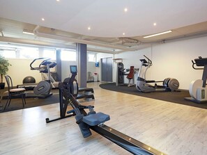 Un gimnasio con diverso equipo de ejercicios, incluyendo cintas de correr, bicicletas estáticas y máquinas de pesas.