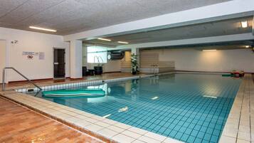 An indoor swimming pool with tiled walls and a wooden floor.