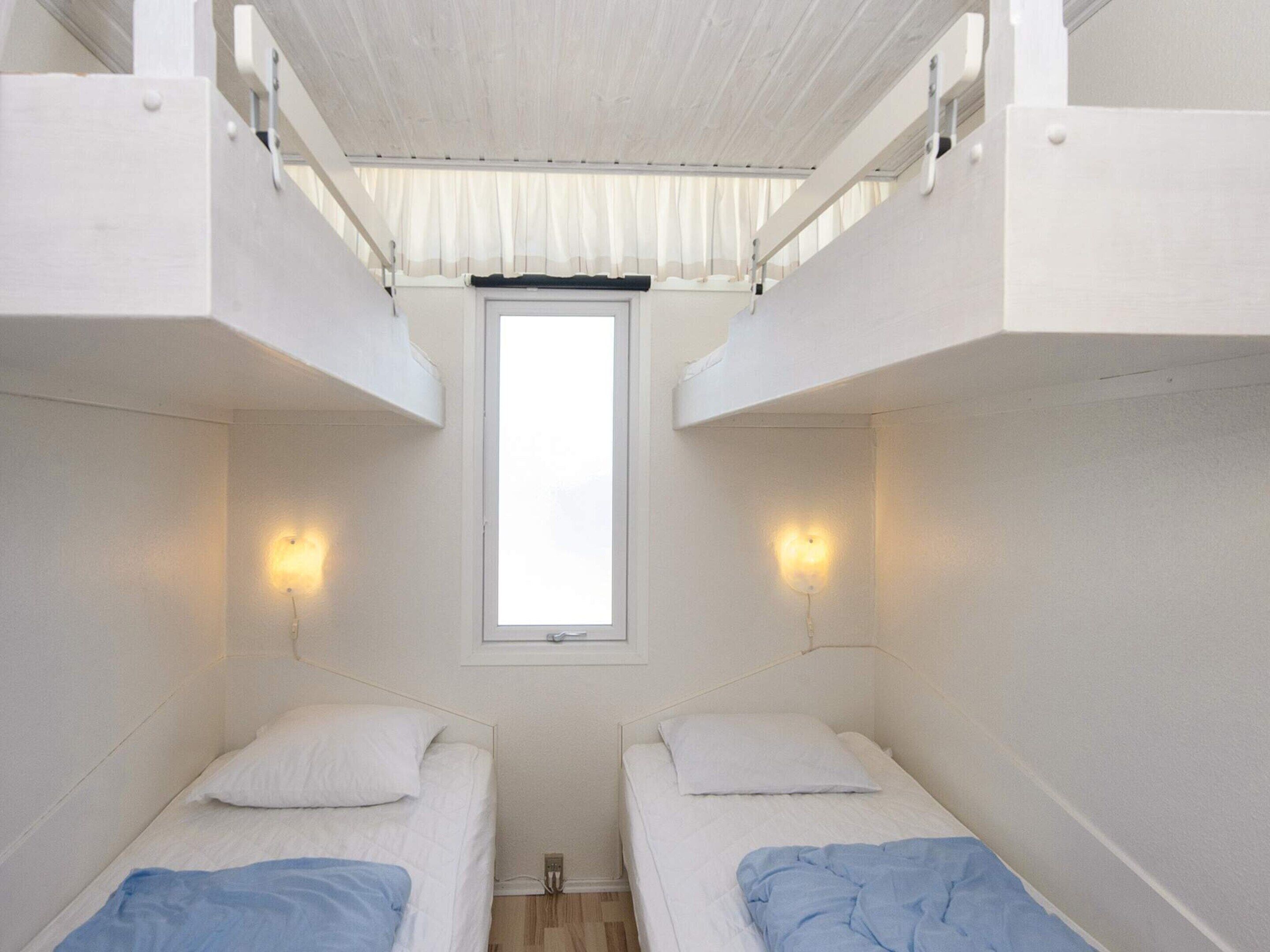 Un dormitorio con literas, una ventana y luces fijadas a la pared.