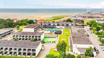 A coastal hotel with multiple buildings, a swimming pool, and a parking area.